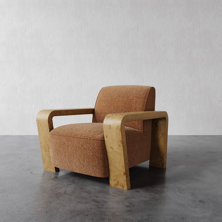 Lemieux et Cie Dumas Lounge Chair with curved arms and warm upholstery, low-profile lounge chair on concrete floor against white plaster wall.