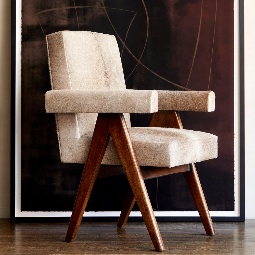 Lemieux et Cie Chaumont Chair in ivory upholstery with angled wood legs, mid-century modern lounge chair before abstract artwork on dark wood flooring.