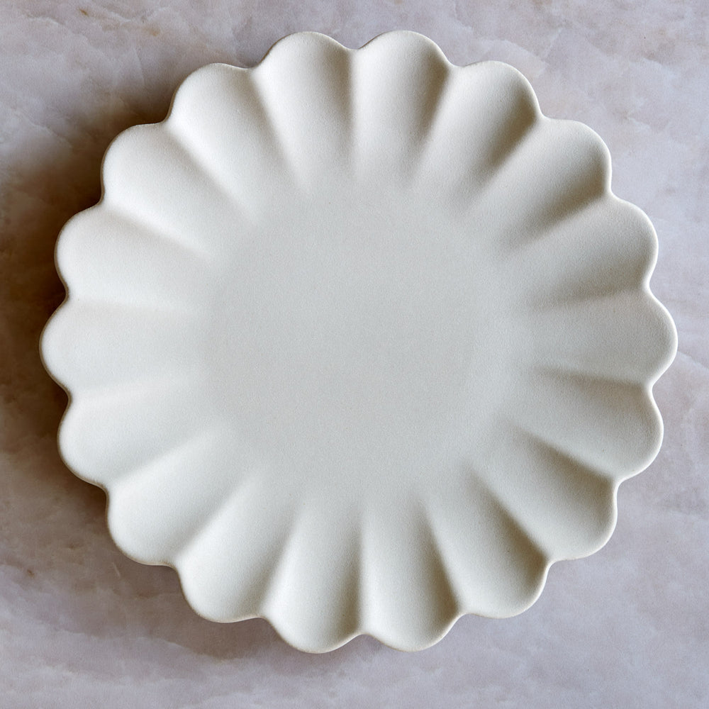 Lemieux et Cie Dhalia Stoneware Salad Plate in white, scalloped ceramic plate with organic petal-shaped edge, shown on pale marble surface.