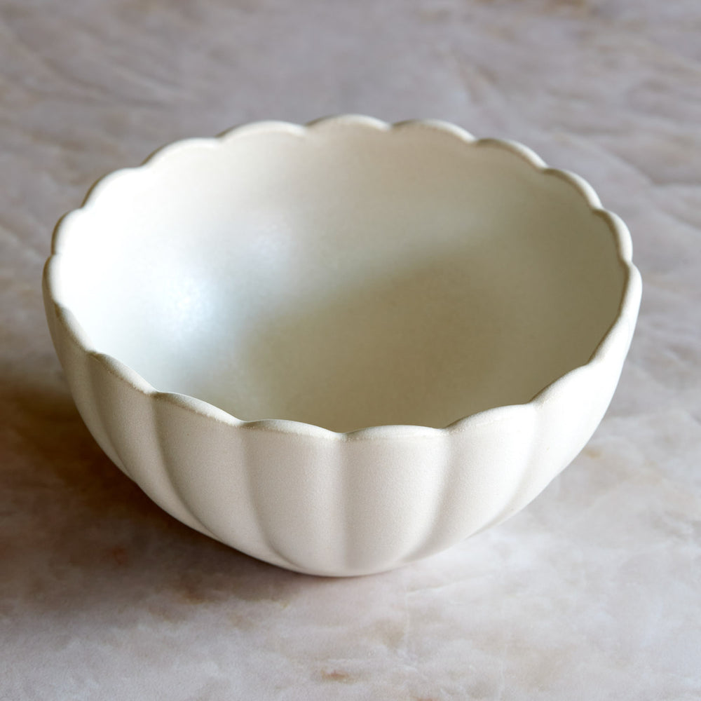 Lemieux et Cie Dhalia Stoneware Bowl in white, scalloped ceramic bowl with fluted edges, shown on neutral stone surface.