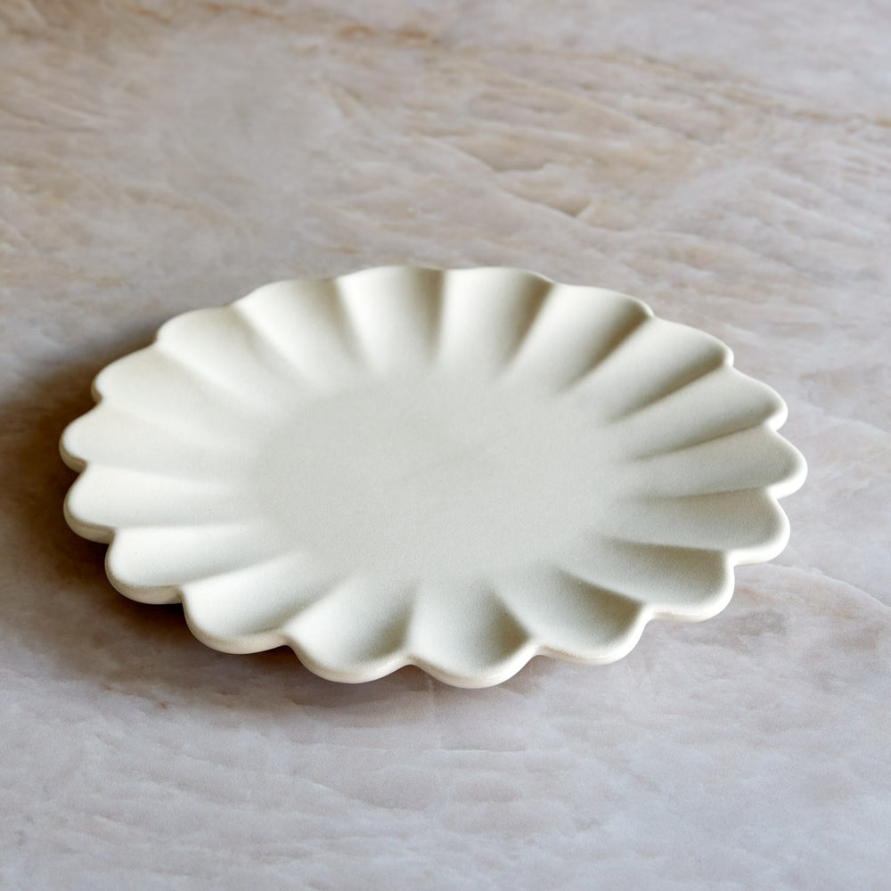 Lemieux et Cie Dhalia Stoneware Salad Plate in white, scalloped ceramic plate with fluted edges, shown on pale marble surface.