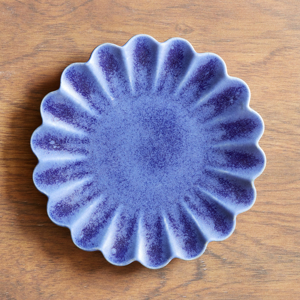 Lemieux et Cie Dhalia Stoneware Salad Plate in blue with scalloped edges, ceramic dish shown on warm wood surface in soft natural light.