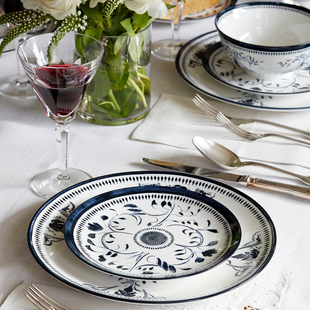 Lemieux et Cie Bruges Porcelain dinnerware set in hand-painted blue and white floral motifs, arranged on white linen tablecloth with glassware and fresh florals.
