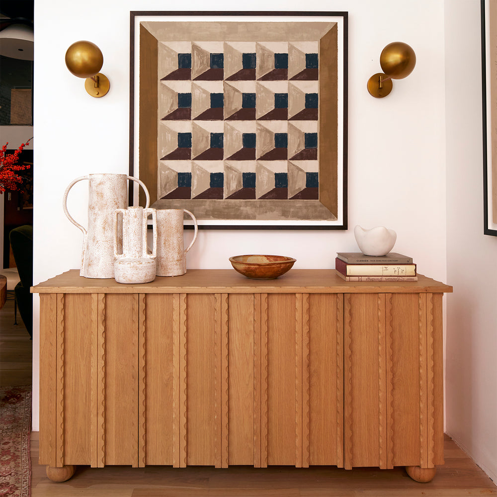 Lemieux et Cie framed geometric print in tan, navy and brown, float mounted artwork displayed above a fluted console with warm sconces on white walls.