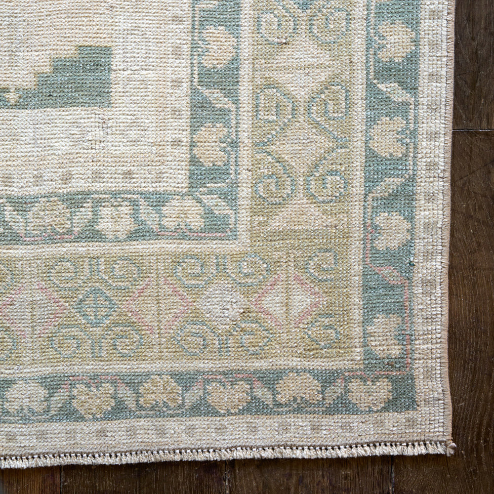 Lemieux et Cie Vintage 1960's Anatolian rug in ivory, sage green and blush with geometric medallion pattern, handwoven vintage rug on dark wood floor.