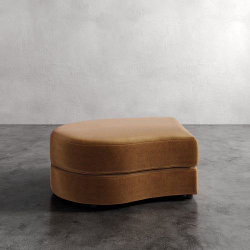 Brown ottoman on a gray concrete floor with a white wall background
