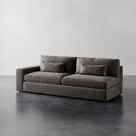 Lemieux et Cie Lacroix Left Arm Sofa in charcoal upholstery, modular sofa with bolster pillows, shown on polished concrete floor against white walls.