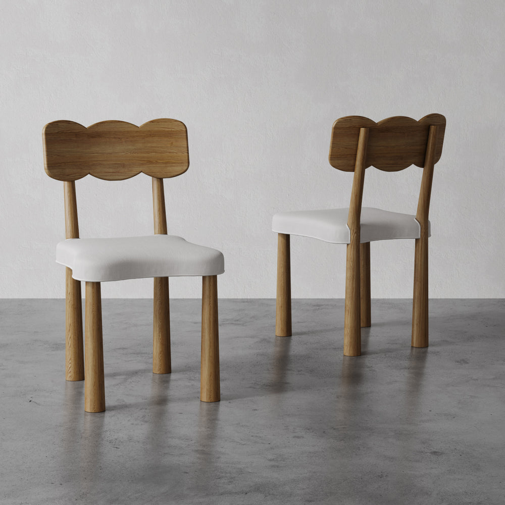 Lemieux et Cie dining chair in walnut-finished solid oak with ivory upholstered seat and sculptural bow-shaped back, shown on polished concrete floor.