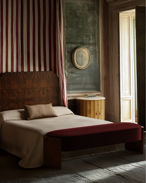 Lemieux et Cie Avenir Bed with low-profile frame and warm-toned upholstered bench, bedroom with carved wood paneling and soft daylight