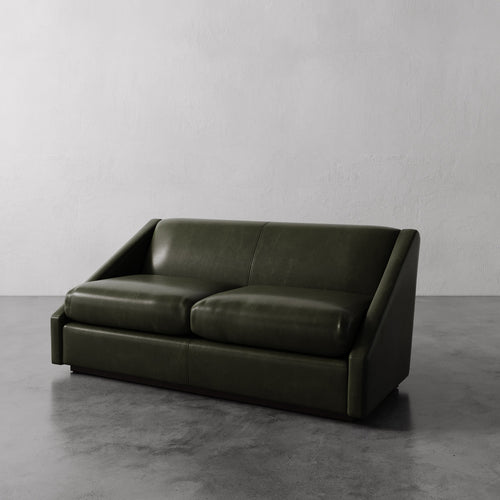 Lemieux Et Cie dark green Fontaine Leather Sofa on a gray floor with a plain white wall background