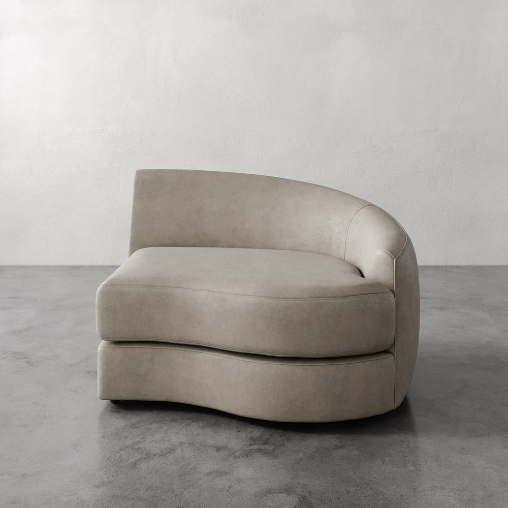 Lemieux et Cie Rulmann Right Arm Chair in warm taupe leather, curved organic form, shown on polished concrete floor against neutral plaster walls.