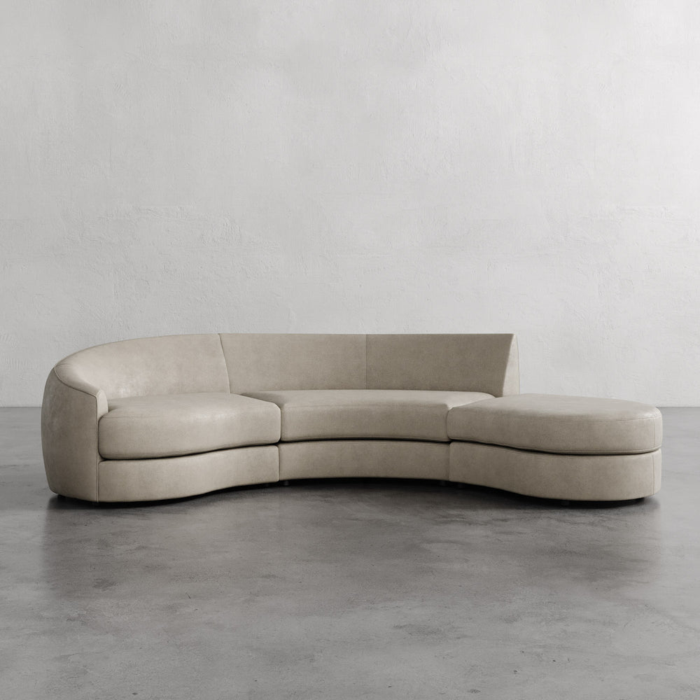 Lemieux et Cie Rulmann 3-Piece Left Sectional in neutral tone, curved modular sofa on concrete floors against textured plaster walls.