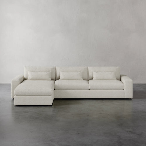 Lemieux et Cie Lacroix Left Chaise Sectional in ivory, low-profile modular sofa with chaise extension, shown on polished concrete floor against neutral plaster walls.