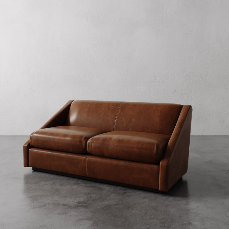 Lemieux Et Cie Brown Fontaine Leather Sofa on a gray floor with a plain white wall background