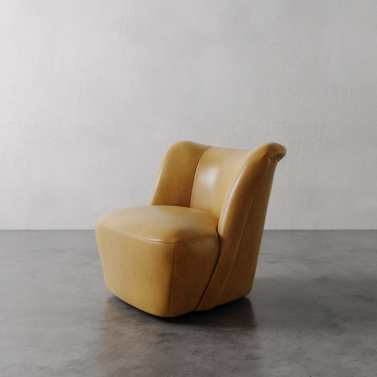 Lemieux et Cie Aurélie Leather Swivel Chair in warm tan leather, sculptural rounded form on polished concrete floor against textured plaster walls.