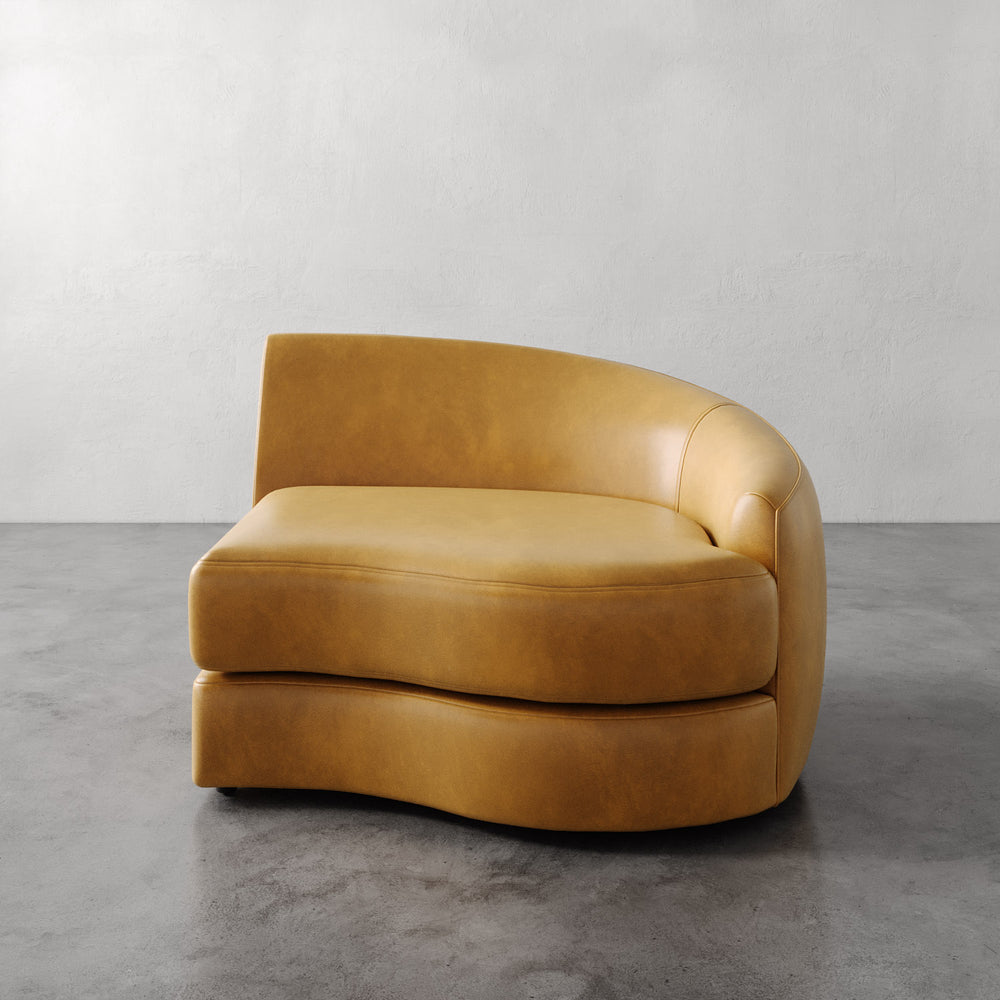 Lemieux et Cie Rulmann Right Arm Chair in warm tobacco leather, curved sculptural form with rounded back, on polished concrete floor.