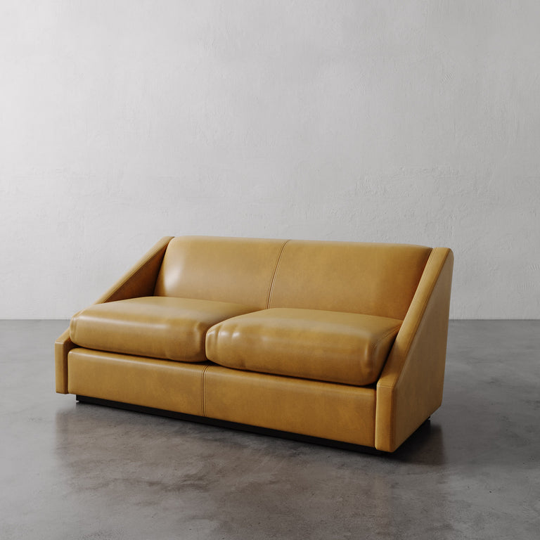 Lemieux Et Cie Tan Fontaine Leather Sofa on a gray floor with a plain white wall background
