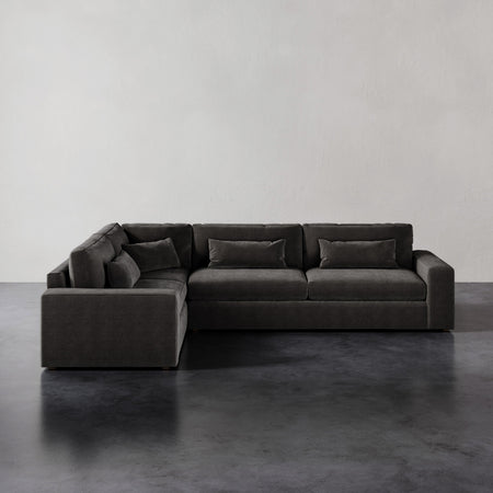Lemieux et Cie Lacroix Right Arm Sectional in charcoal, modular L-shaped sofa with bolster pillows, on dark concrete floor against white walls.