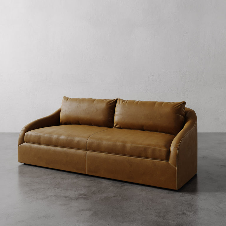 Lemieux Et Cie Chestnut Brown Rousseau Leather Sofa on a gray floor with a plain white wall background