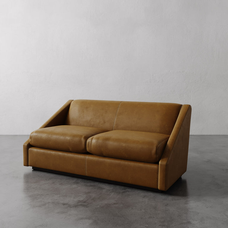 Lemieux Et Cie Chestnut Brown Fontaine Leather Sofa on a gray floor with a plain white wall background