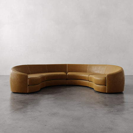 Lemieux et Cie Rulmann 4-Piece Sectional in caramel leather, curved modular sofa with organic rounded form, shown on concrete floor against white walls.