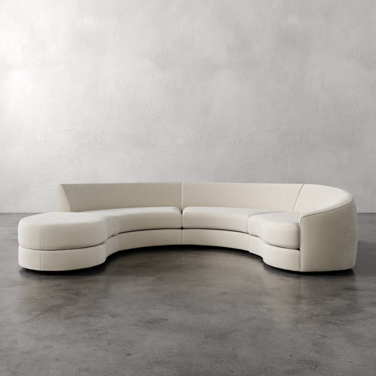 Lemieux et Cie Rulmann 4-Piece Right Sectional in ivory, curved modular sofa shown on polished concrete floor against textured plaster walls.