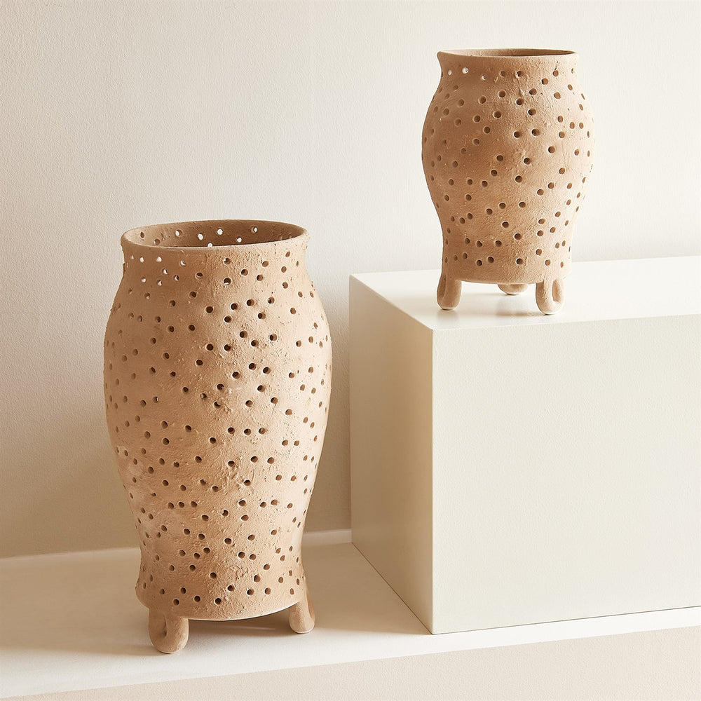 Lemieux et Cie Yassine Candle Holder in beige, ceramic vessels with hand-pierced perforations on footed bases, shown on neutral plinth and surface.