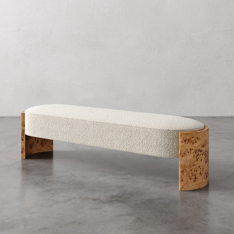 Lemieux et Cie Benoit Custom Upholstered Bench in ivory bouclé with curved Maple burl legs, shown on polished concrete floor against neutral plaster walls.