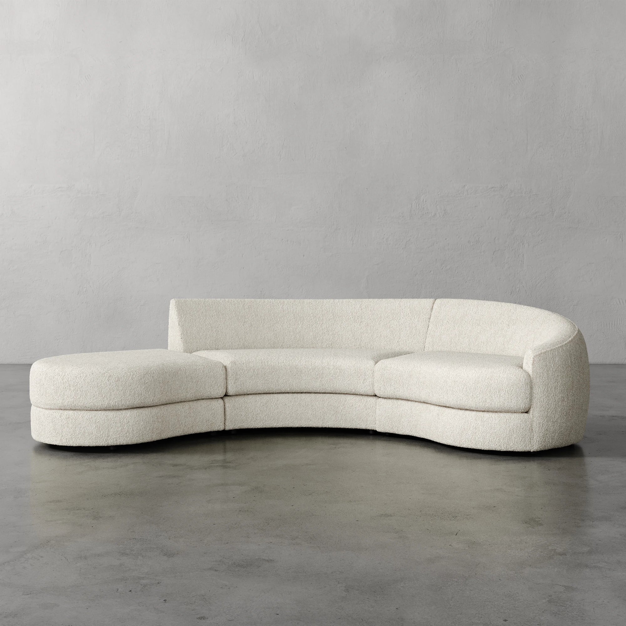 Lemieux Et Cie Rulmann 3-Piece Right Sectional Modern curved sofa in a minimalistic setting with a plain gray wall and floor.