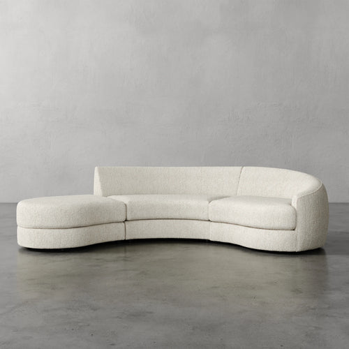 Lemieux Et Cie Rulmann 3-Piece Right Sectional Modern curved sofa in a minimalistic setting with a plain gray wall and floor.
