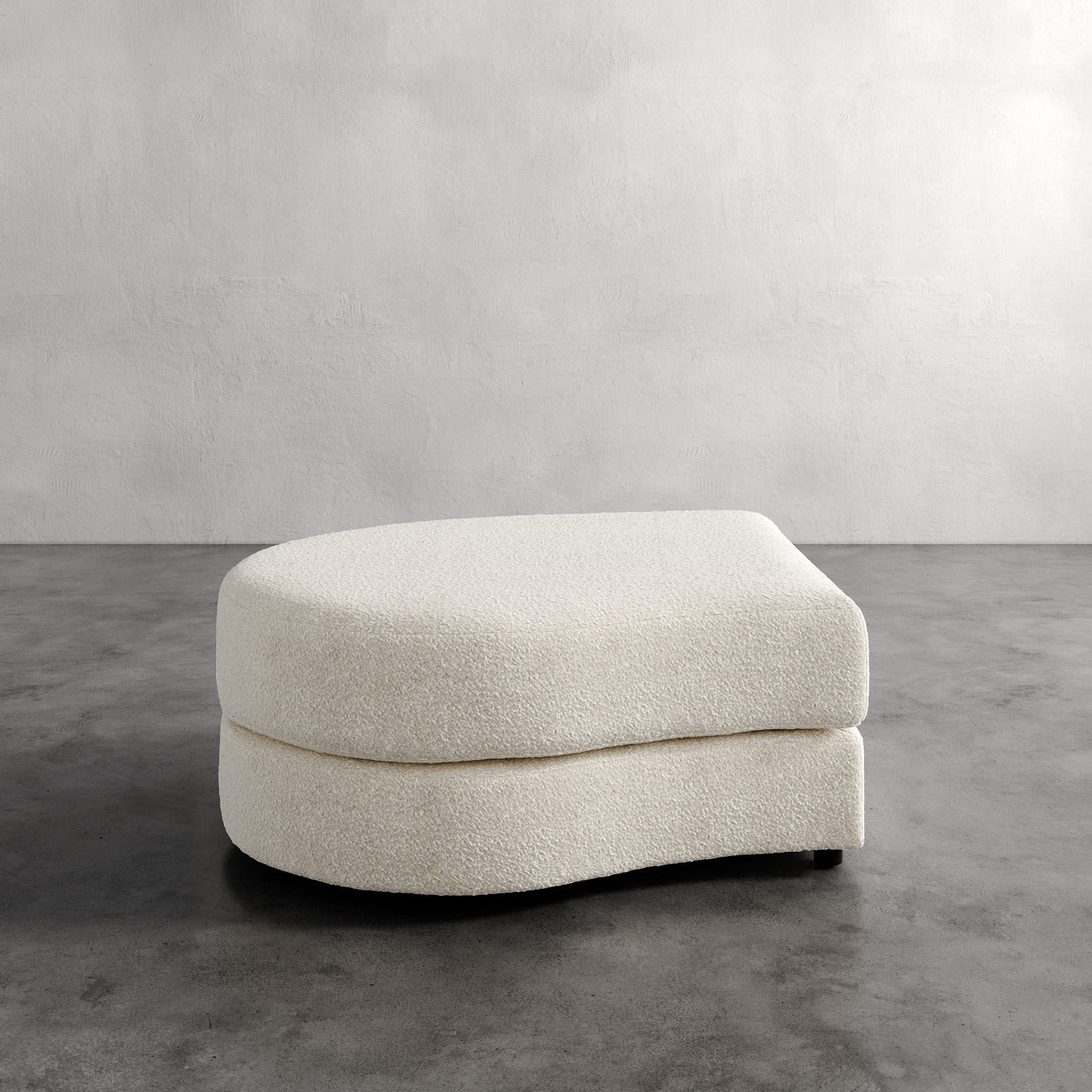 Lemieux Et Cie Rulmann Left Ottoman Beige ottoman on a gray floor with a plain wall background