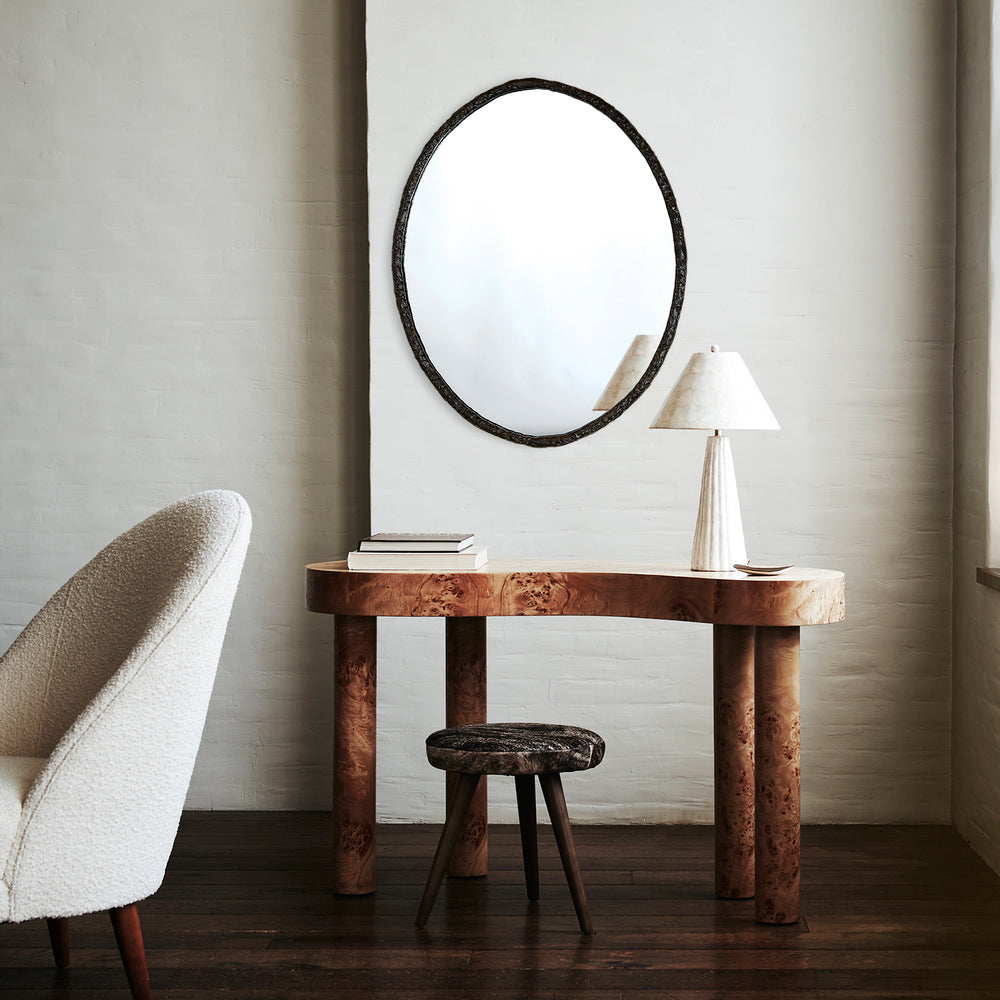 Lemieux et Cie Berger Mirror, large oval mirror with dark textured frame, hung above burl wood console with table lamp on neutral plaster walls.