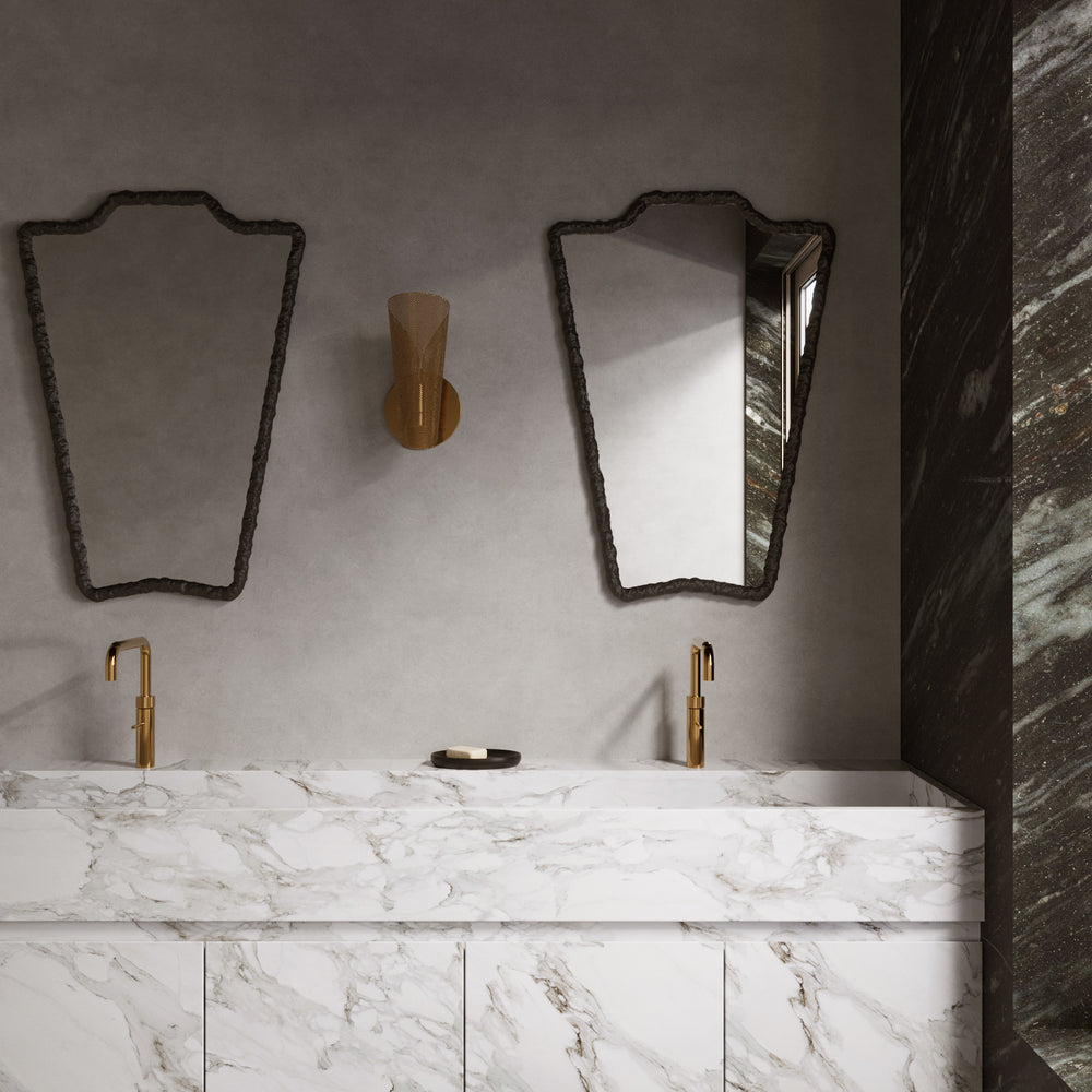 Lemieux et Cie Bouclier Mirror with hand-hammered cast iron frame in bathroom setting, above marble double vanity with brass faucets and plaster walls.