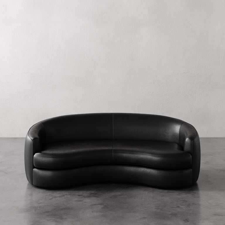 Lemieux et Cie Black Rulmann leather sofa on a gray floor with a light gray wall background