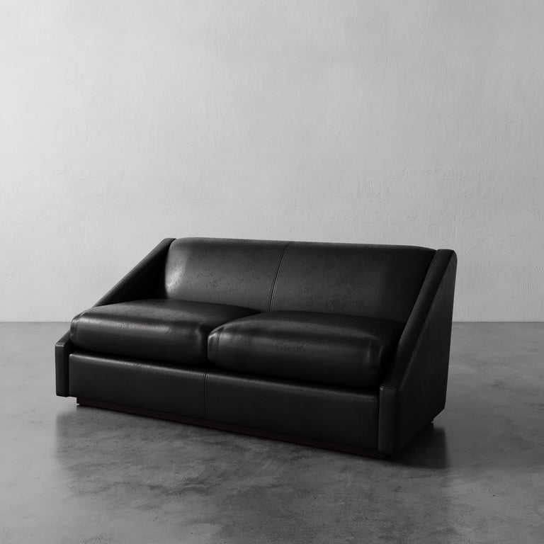 Lemieux Et Cie black Fontaine Leather Sofa on a gray floor with a plain white wall background.