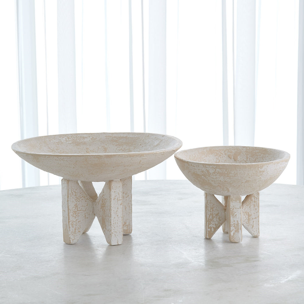 Lemieux et Cie Loire Bowl in natural washed finish, sculptural bowls with geometric feet, shown in two sizes on pale stone surface before white curtained backdrop.
