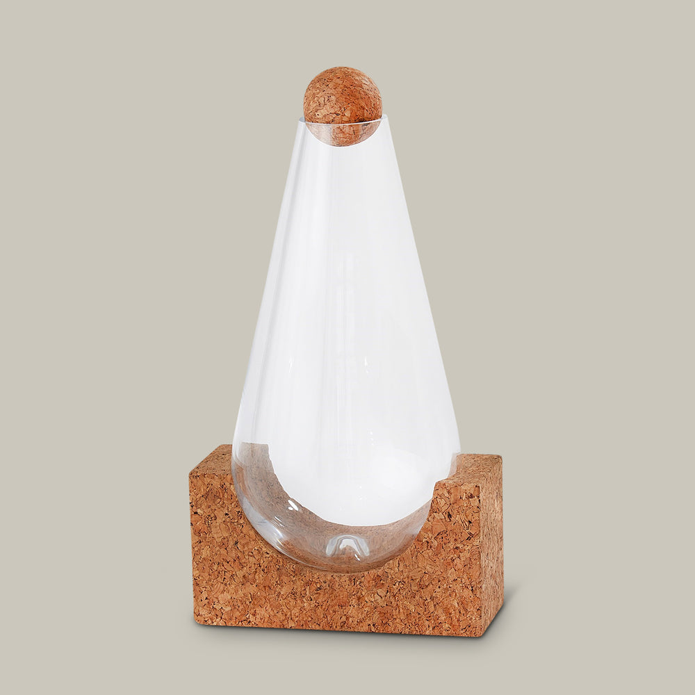 Lemieux et Cie glass decanter with cork base and spherical stopper, tapered vessel on geometric form, shown against neutral studio backdrop.