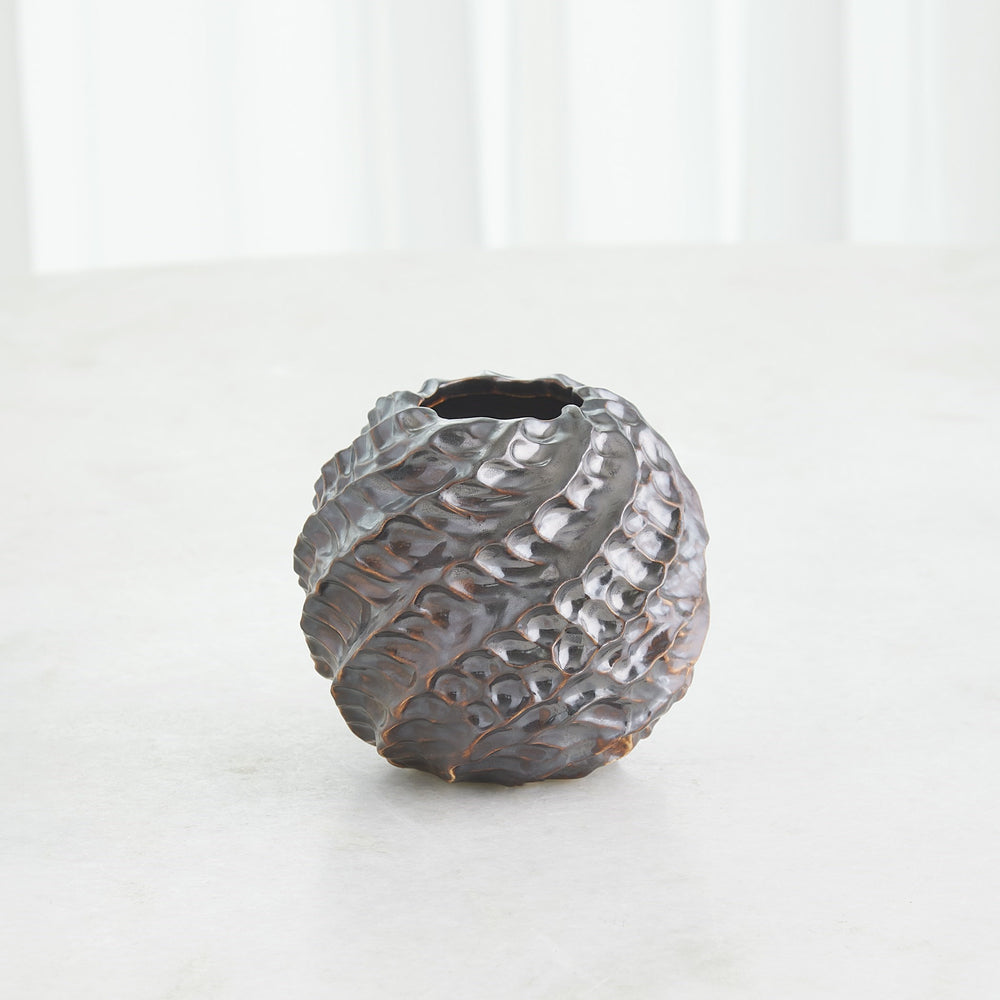 Lemieux et Cie handmade ceramic vase with textured pinched surface, organic spherical form in warm charcoal glaze, shown on light stone surface in soft daylight.