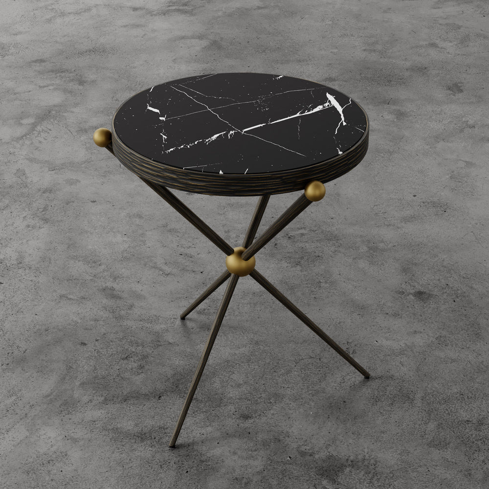 Lemieux et Cie Cambert Round Side Table with honed Nero Marquina marble top and bronze iron frame with aged brass ball details, shown on concrete floor.