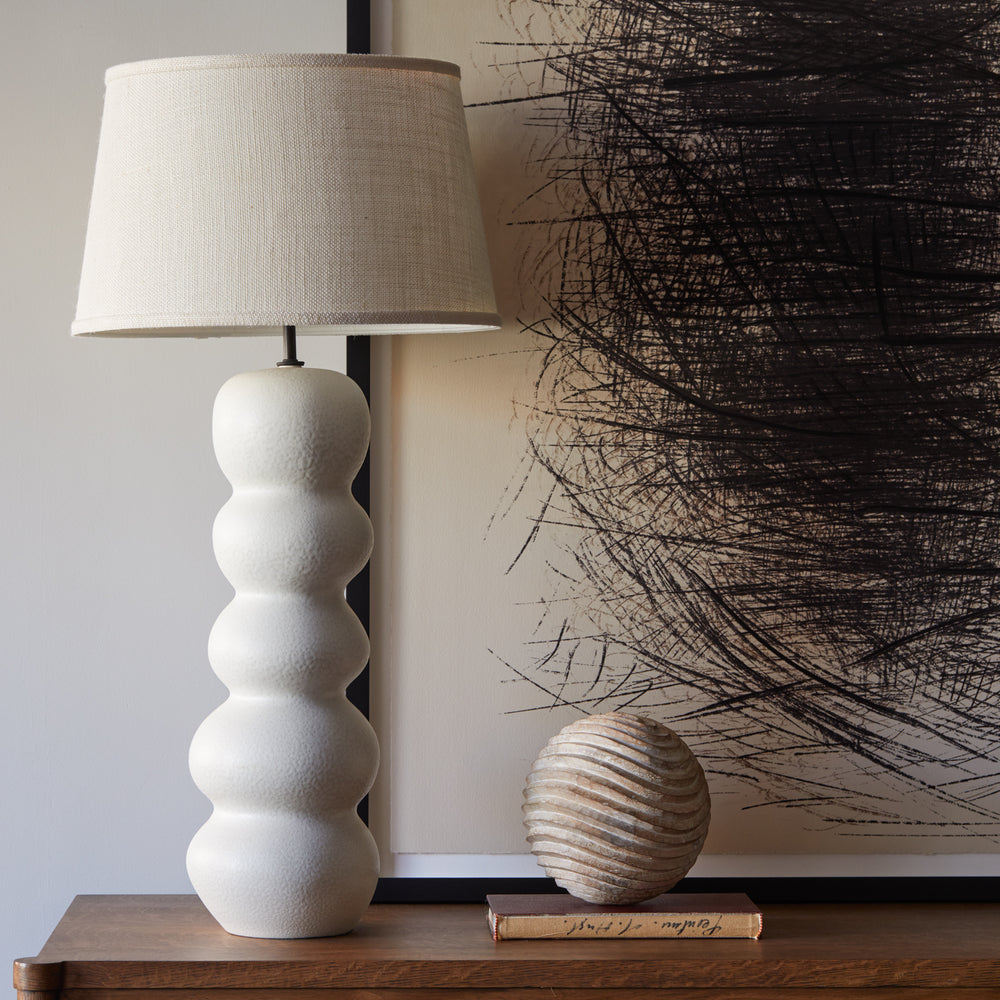 Lemieux et Cie Moulard Wooden Sphere with layered horizontal ridges, sculptural object shown on wood table beside textured table lamp and abstract artwork.
