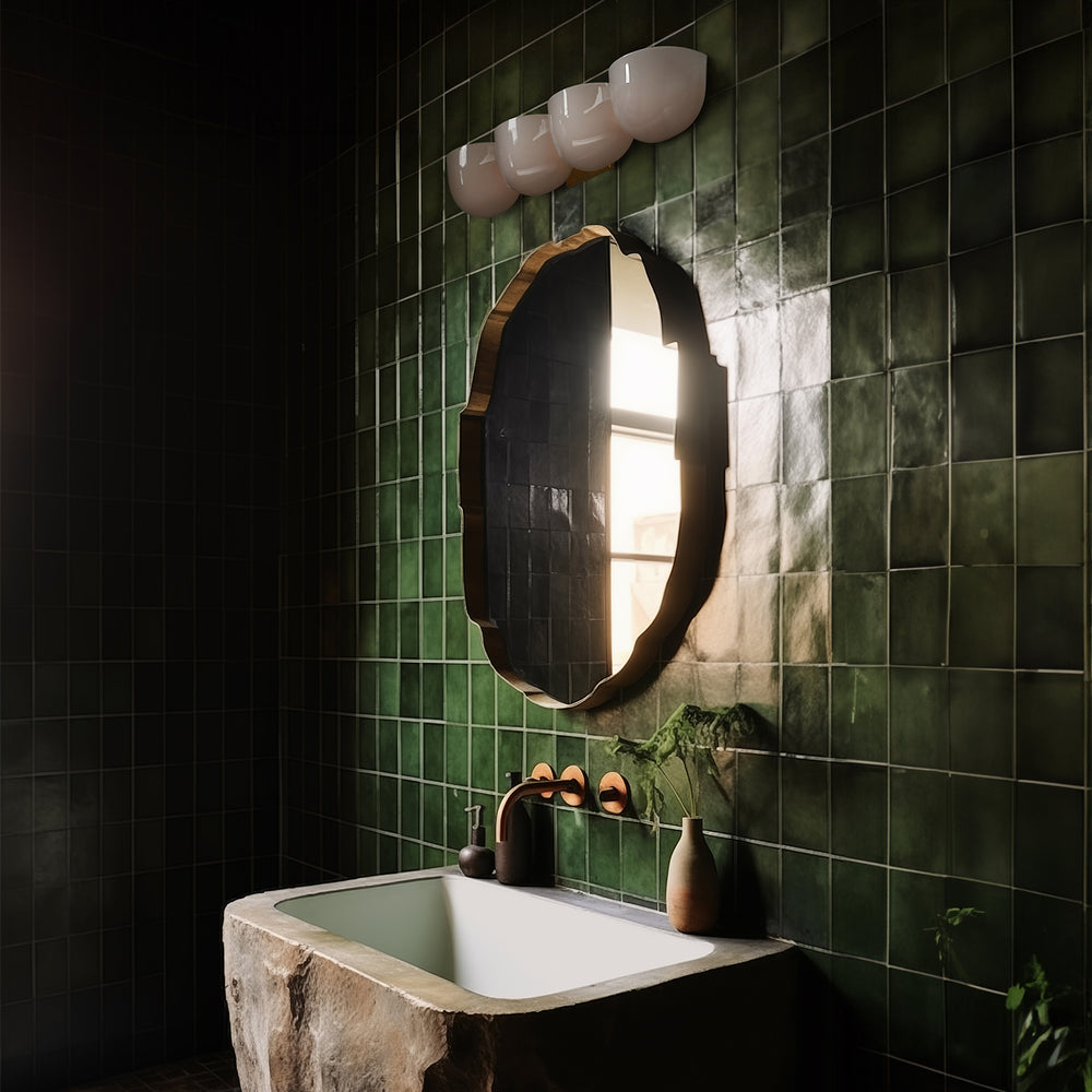 Lemieux et Cie Cocoon Lamp in white resin with sculptural ovoid form, sconce mounted above organic mirror and stone sink in green tiled bathroom.