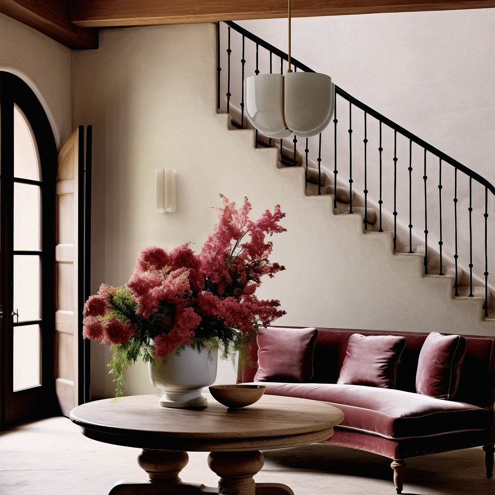 Lemieux et Cie Cheverny Large Pendant, a luxury lighting fixture with a white milk glass shade and burnished brass stem, hanging above a seating area with layered furnishings and a Cheverny Long Sconce on the wall.