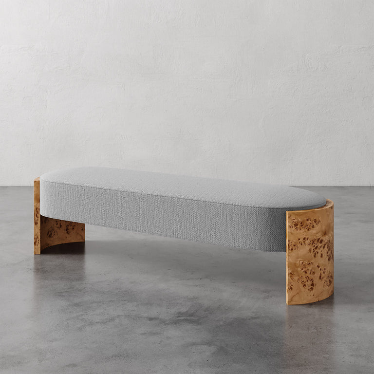Lemieux et Cie Benoit Custom Upholstered Bench with curved Maple burl legs and upholstered seat, shown on polished concrete floor against neutral plaster walls.