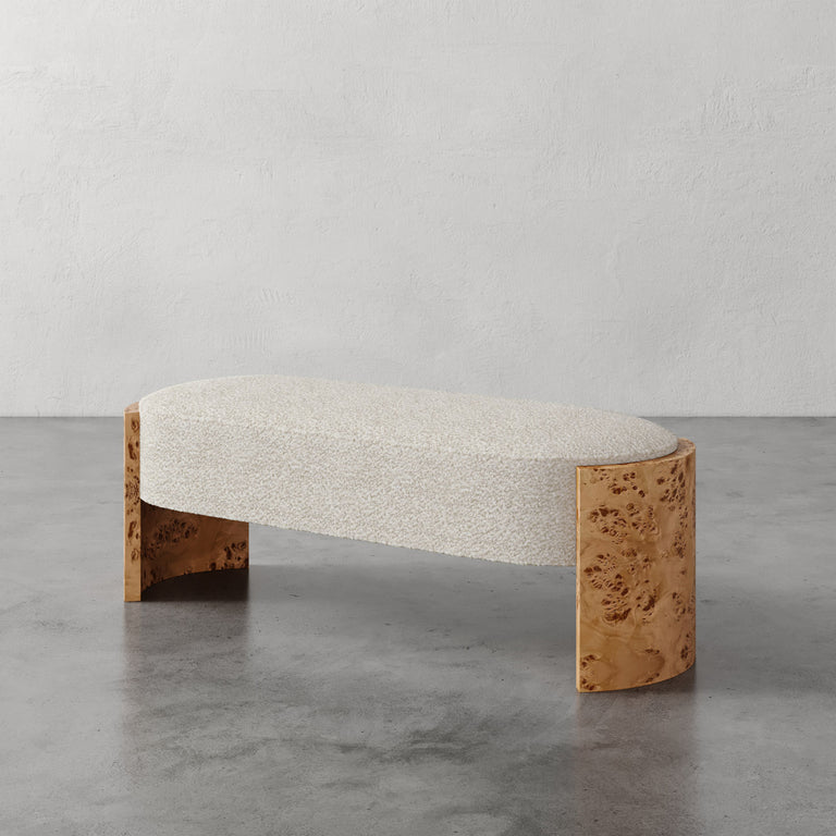 Lemieux et Cie Benoit Upholstered Bench with curved Maple burl legs and ivory bouclé seat, sculptural bench on polished concrete floor against plaster walls.