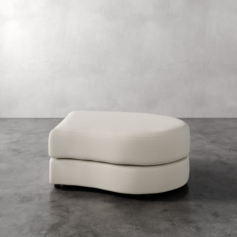 Lemieux Et Cie Rulmann Right Ottoman Beige ottoman on a gray floor with a white wall background