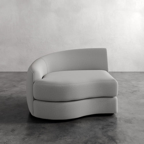 Lemieux Et Cie Rulmann Left Arm Chair Gray curved sofa on a concrete floor with a light gray wall background