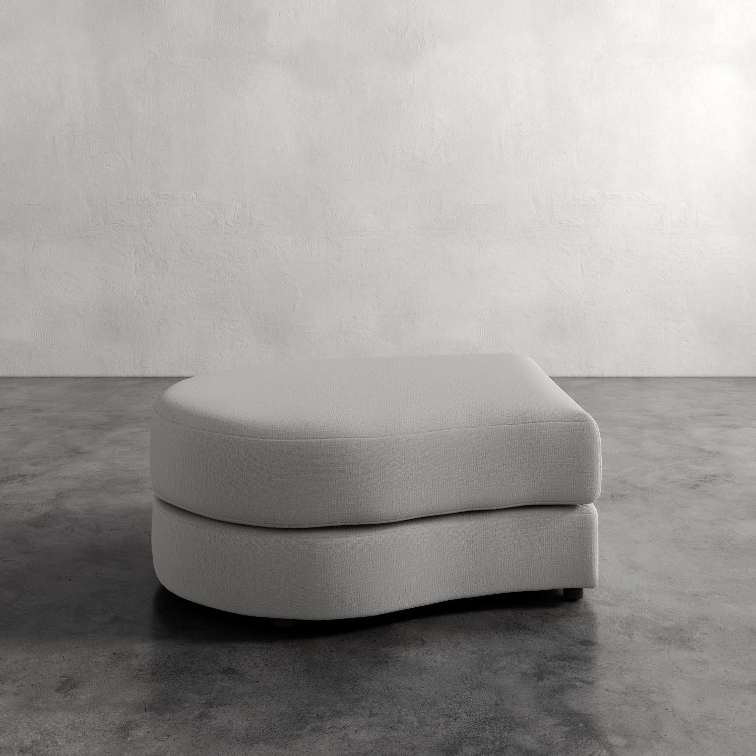 Lemieux Et Cie Rulmann Left Ottoman Gray ottoman on a concrete floor with a white wall background
