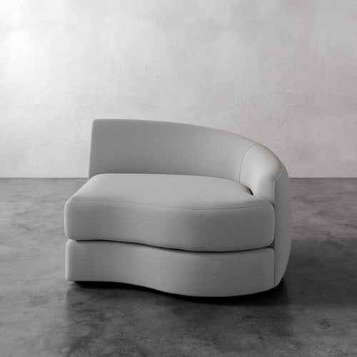 Lemieux Et Cie Rulmann Right Arm Chair Gray curved sofa on a gray floor with a plain white wall background