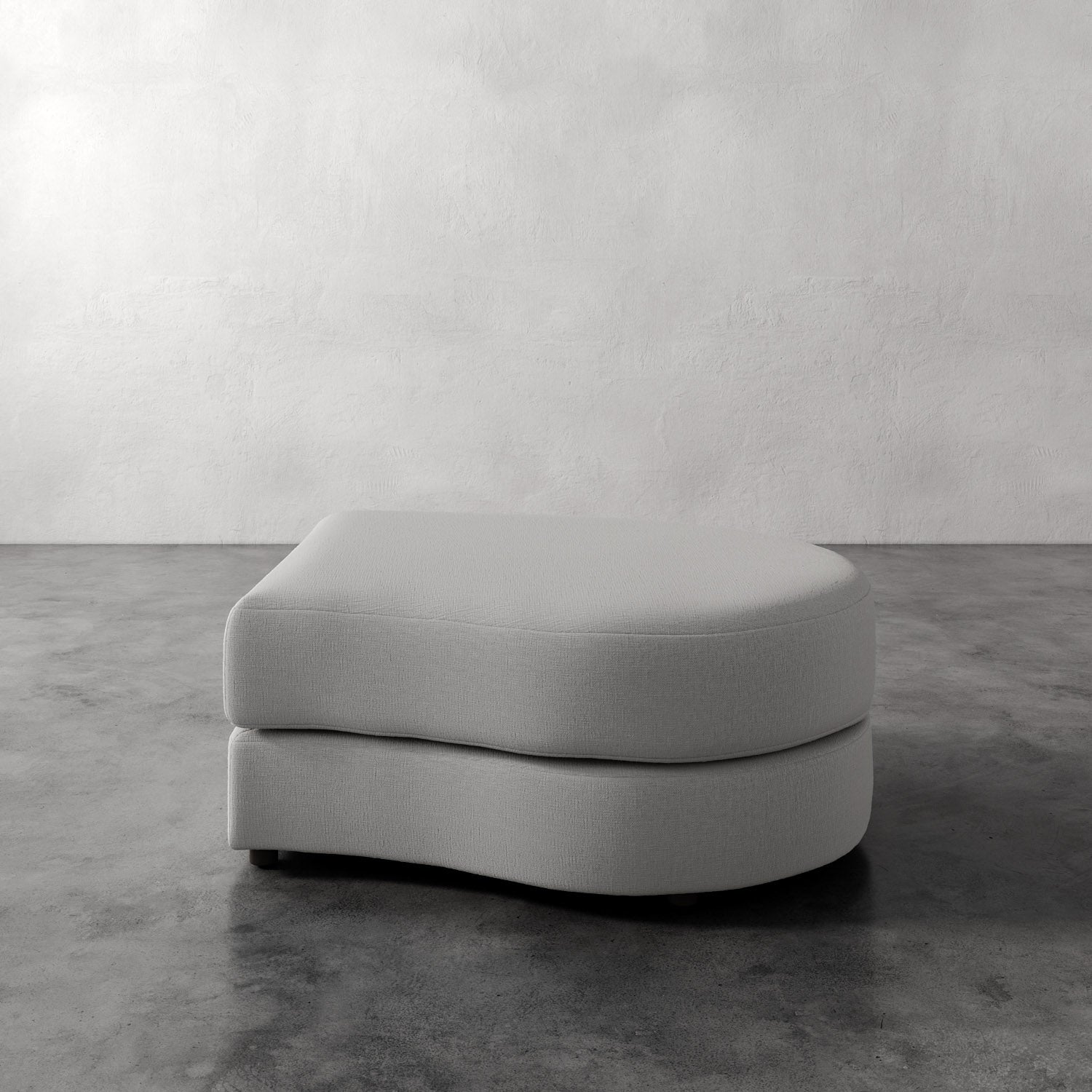 Lemieux Et Cie Rulmann Right Ottoman Gray ottoman on a concrete floor with a white wall background