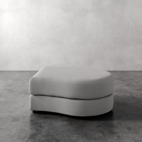 Lemieux Et Cie Rulmann Right Ottoman Gray ottoman on a concrete floor with a white wall background